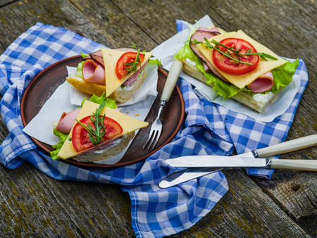 Sandwich with ham, cheese and tomato on plate and on tableの写真素材