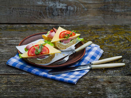 Sandwich with ham, cheese and tomato on plate and on tableの写真素材