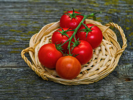 Bunch of fresh tomatoes and tomato juice in glass on wooden tableの写真素材