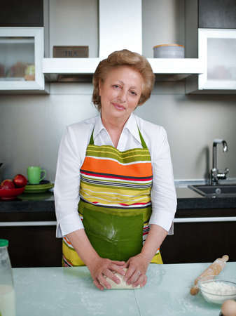 Happy elderly woman in the kitchen holding cooked dumplings and showing thumbs up.の写真素材