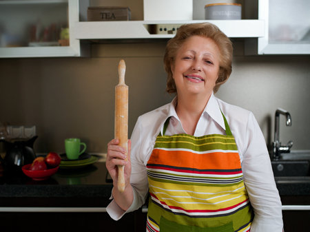 Happy elderly woman in the kitchen holding cooked dumplings and showing thumbs up.の写真素材