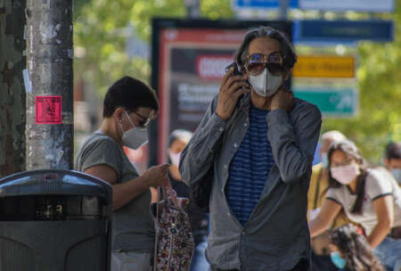 Madrid / Spain - 06/18/2020: Men with two glasses speaking with his mobile phone on the street. New situation in Spain about the pandemic of Covid-19. People are using mask in their new life routine.のeditorial素材