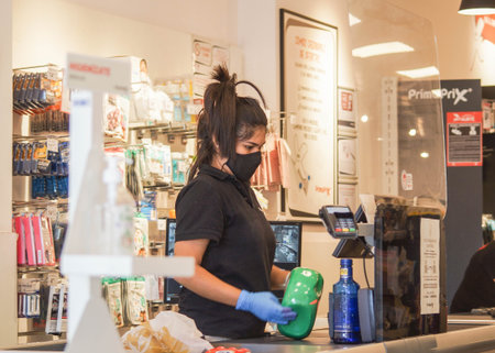 Madrid / Spain - 07 13 20: young woman working on a shopping and wearing a black face mask