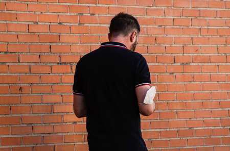 Madrid / Spain - 07 13 20: bad use of face mask in pandemic Covid-19. A man is wearing his mask over his elbow on the streetのeditorial素材