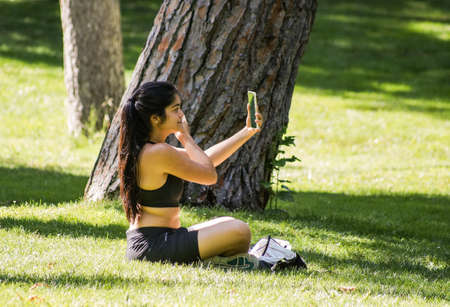 Madrid / Spain - 07 23 20: Girl doing selfie in Retiro park in the summer.のeditorial素材