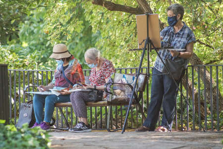 Madrid / Spain - 07 23 20: Group of three people painting in Retiro park and using face maskのeditorial素材