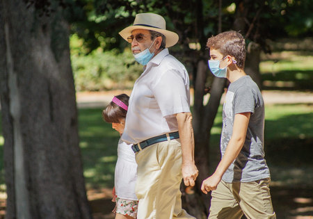 Madrid / Spain - 07 23 20: Grandfather and two grandsons walking on the park in the summerのeditorial素材