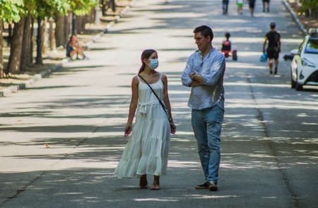Madrid / Spain - 07 23 20: Couple walking at Retiro park in the summer. Just the girl is using face maskのeditorial素材
