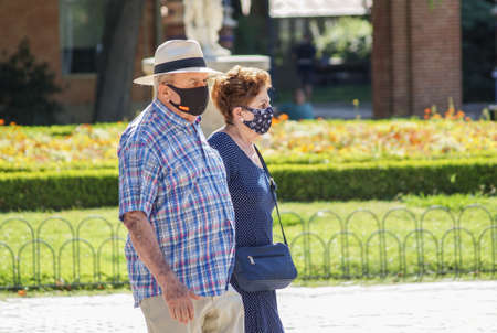 Madrid / Spain - 07 23 20: Retired couple on Retiro park using face mask in the summer. One face mask is with Spain flag.のeditorial素材