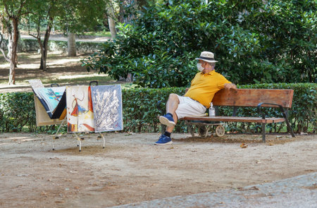 Madrid / Spain - 07 23 20: Merchant in Retiro park selling his peace of art and using hi face mask in the summerのeditorial素材