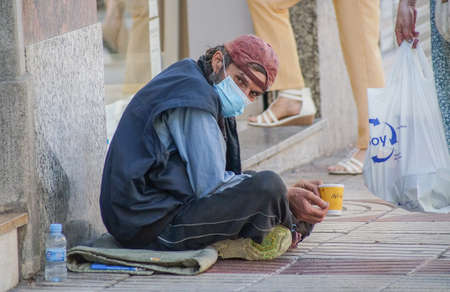 Madrid, Spain / 08 19 20: Coronavirus crisis in Madrid. Homeless on the street asking for money and wearing face mask.のeditorial素材