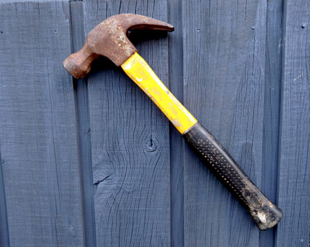A well used hammer hanging in a wooden steel blue wall...