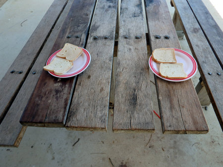 Slices of white bread on a white place on top of a picnic table