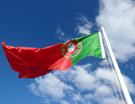 Waving portuguese flag on sunny blue sky, portugal.の写真素材
