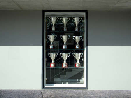 silver cup trophies on glass display window outsideの写真素材
