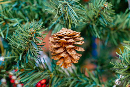Pine cone on a christmas tree. Christmas concept. Artificial pine branches in the background.の写真素材