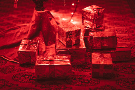 Handmade christmas present under christmas tree. Red christmas lights illuminates the gift box.