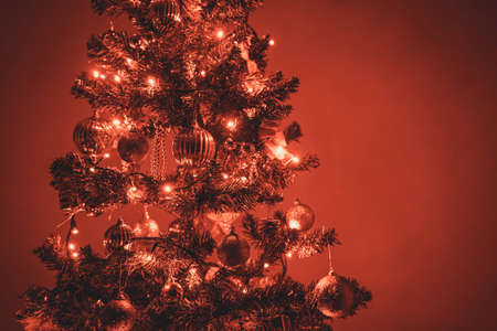 Photo of a christmas tree with red christmas lights and christmas ornaments. Space for copy or text on the right side of the picture.の写真素材
