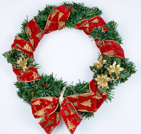 Christmas wreath isolated on white background. Red ribbon on green artifical pine and red bow, golden flowers.の写真素材