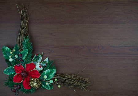Christmas wreath isolated on wooden background. Big red flower and green leaves and twigs. Space for text or copy. Christmas or New Year.の写真素材