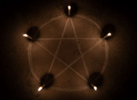 White pentagram symbol on concrete ground. Illuminated with candles. Dark background. Scary, mystical occultismの写真素材