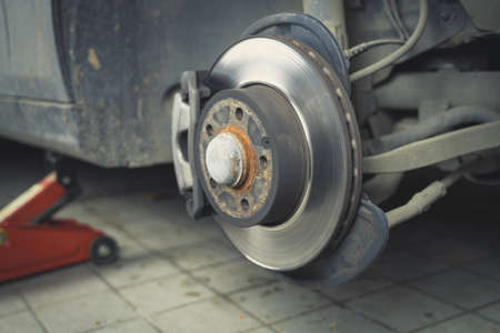 Car without wheel and lift up by hydraulic, waiting for tire replacement in a garage.の写真素材