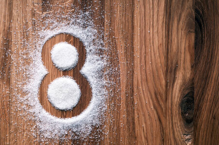 Grains of sugar in shape of eight on wooden  の写真素材