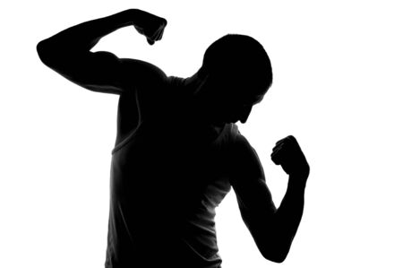 Silhouette of young strong man looking on his biceps  On white background の写真素材