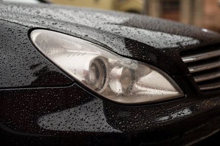 Modern car headlights with water drops. Transportation background.