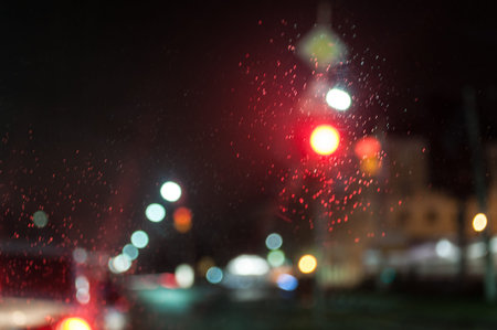 Red light. View through the windshield of the car. Raindrops on the glass. Blurry photo. Night in...