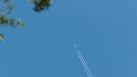 airliner in the sky. the plane flies leaving a contrail of working engines. plane against the blue sky. Passenger airliner. Travel by plane.の写真素材