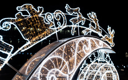 Christmas installation Santa Claus in a sleigh pulled by reindeer with gifts. beautiful, glowing holiday installation in the city before Christmas and New year. new Year and Christmas mood.の写真素材
