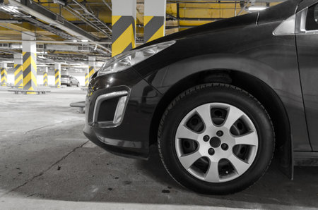 the car is parked in an underground parking lot. contrasting color in the background, dark color of...