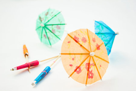 Different colors of cocktail umbrellas on a white background.
