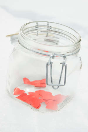 Red  paper hearts in a jar on a snow winter background.の写真素材