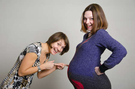 Pregnant woman and girfriend expecting baby over grayの写真素材