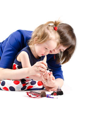 Mom teaches daughter to paint nails on white backgroundの写真素材