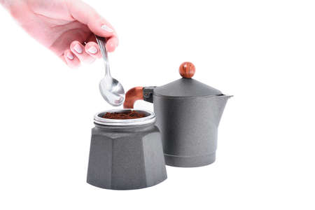 Hand pours coffee into a geyser coffee maker on a white background, shallow depth of fieldの写真素材