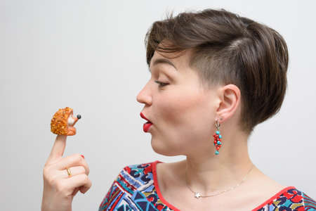 Portrait of a girl with a ceramic hedgehog on a gray backgroundの写真素材