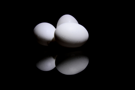 Three eggs with reflection lying on a black backgroundの写真素材