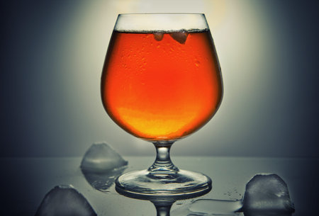 Whiskey, bourbon, brandy or cognac with ice on a gray background. Design concept.