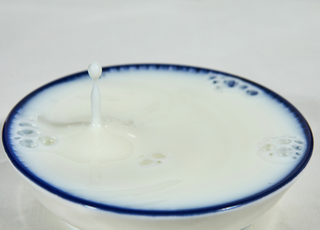 A drop of milk or a white drop of liquid in a bowl with a blue stripe.の写真素材