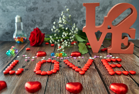 Romantic still life, red rose, chocolate in the shape of hearts and the inscription love on a wooden background. Valentine's day concept. Soft focusの写真素材