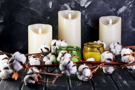 Cotton flowers lying on a dark wooden background and candles behind them.の写真素材