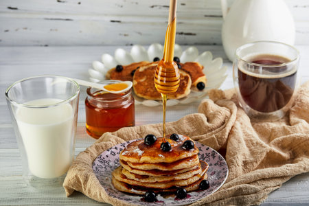 Tasty breakfast. A stack of pancakes with honey syrup a glass of milk, espresso coffee and honey on...