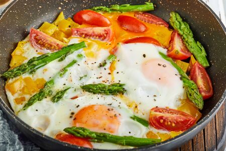 Tasty breakfast. Fried eggs in a pan on a wooden white backgroundの写真素材