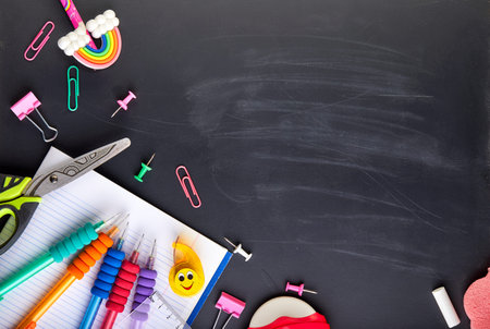 School supplies on black board background with copy space. Back to school concept
