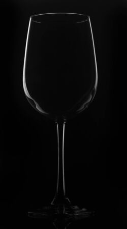Glass of wine on a black background, standing on a black stand with reflection.の写真素材
