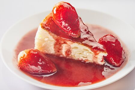 Cheesecake with strawberry jam on a white plate on a light background.の写真素材