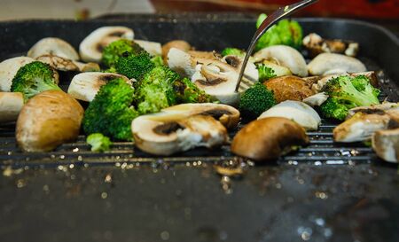 Fresh champignon mushrooms and porcini mushrooms are fried on a board along with broccoli in butter. Healthy eating concept.の写真素材
